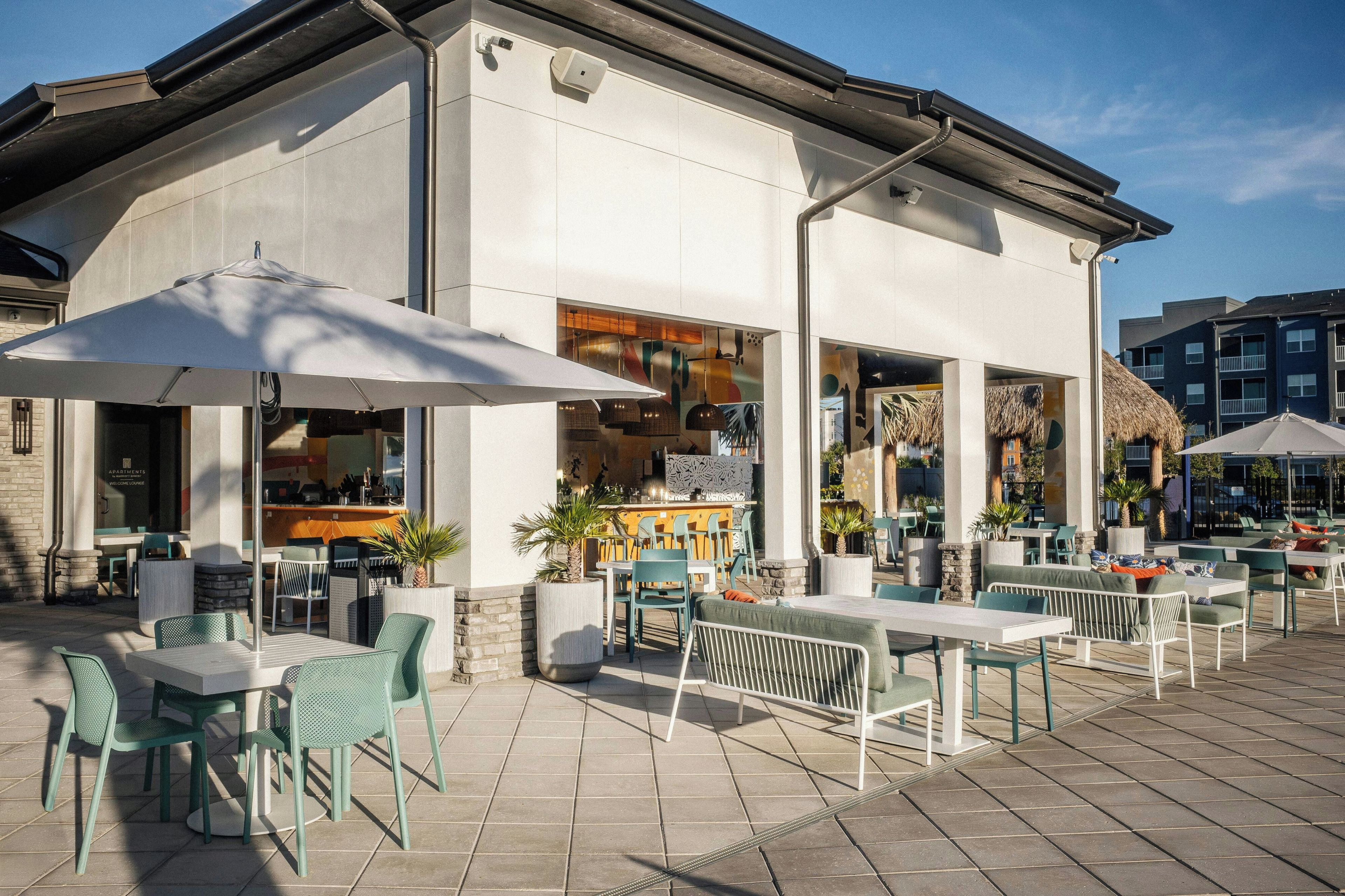 An outdoor seating area with tables and chairs, a bar, and umbrellas.