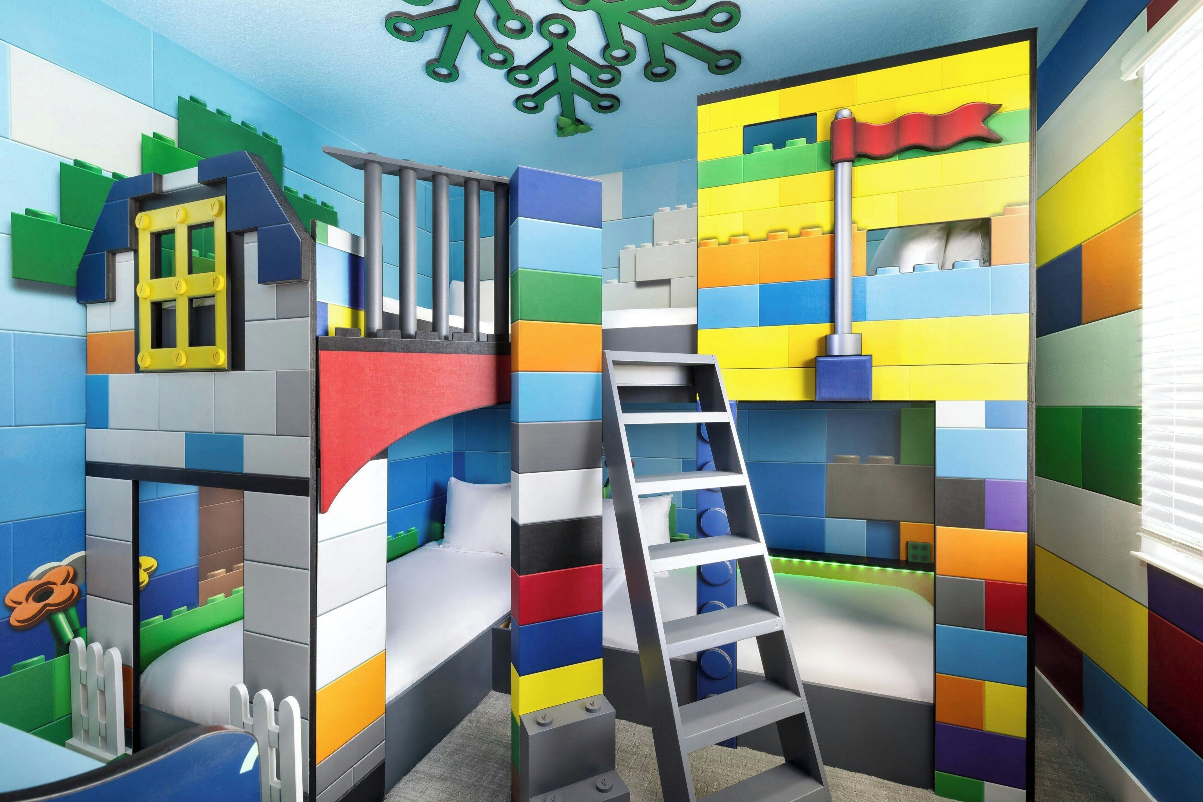 A playroom with colorful block walls, a ladder, and a bed.