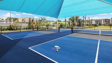 An outdoor tennis court with two courts, a net, and a single tennis ball.