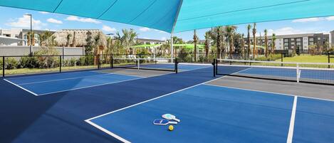 An outdoor tennis court with two courts, a net, and a single tennis ball.