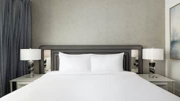 Una habitación de hotel con una cama grande, dos mesitas de noche y un cabecero.
