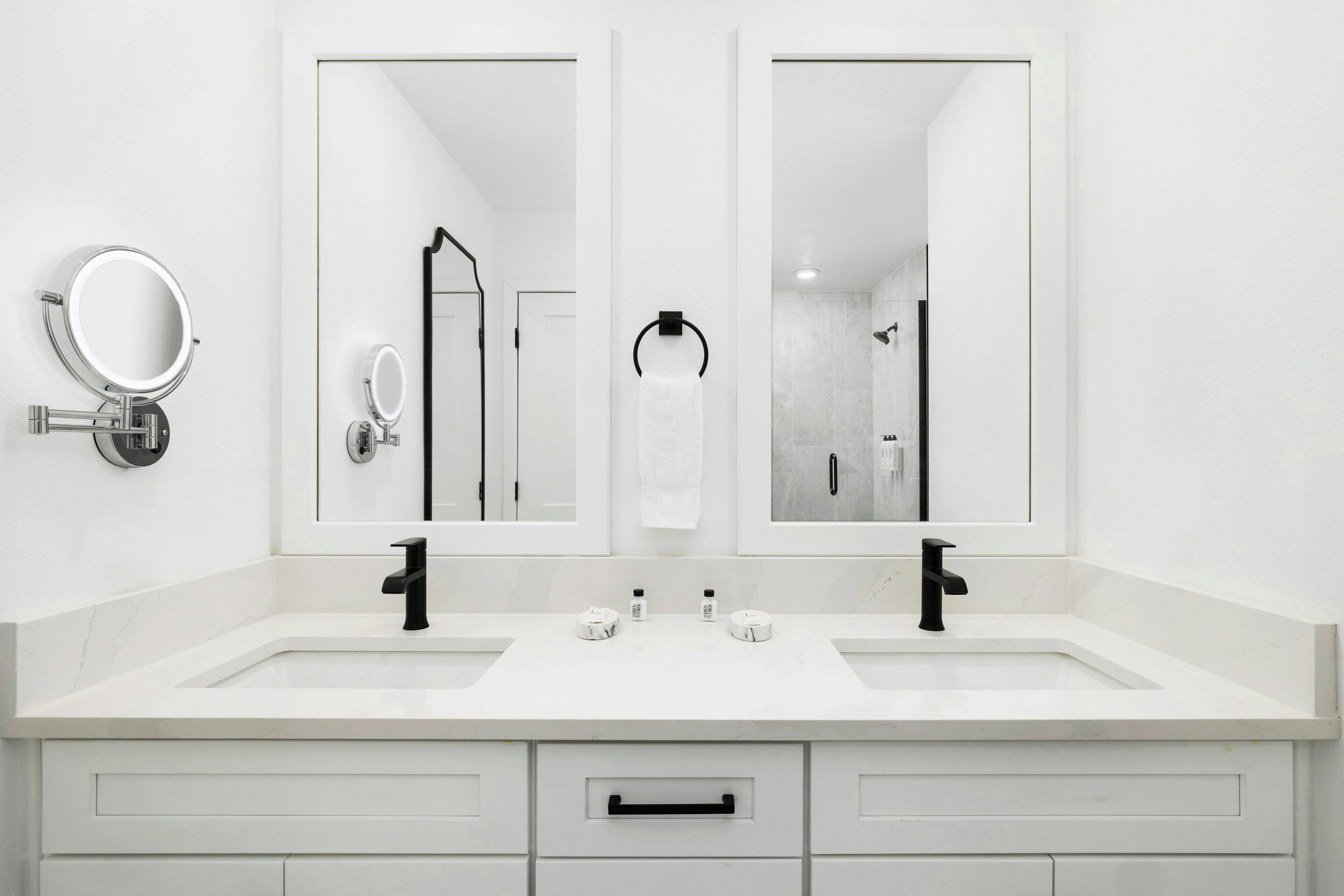 Une salle de bain moderne avec deux lavabos, un miroir et un porte-serviettes.