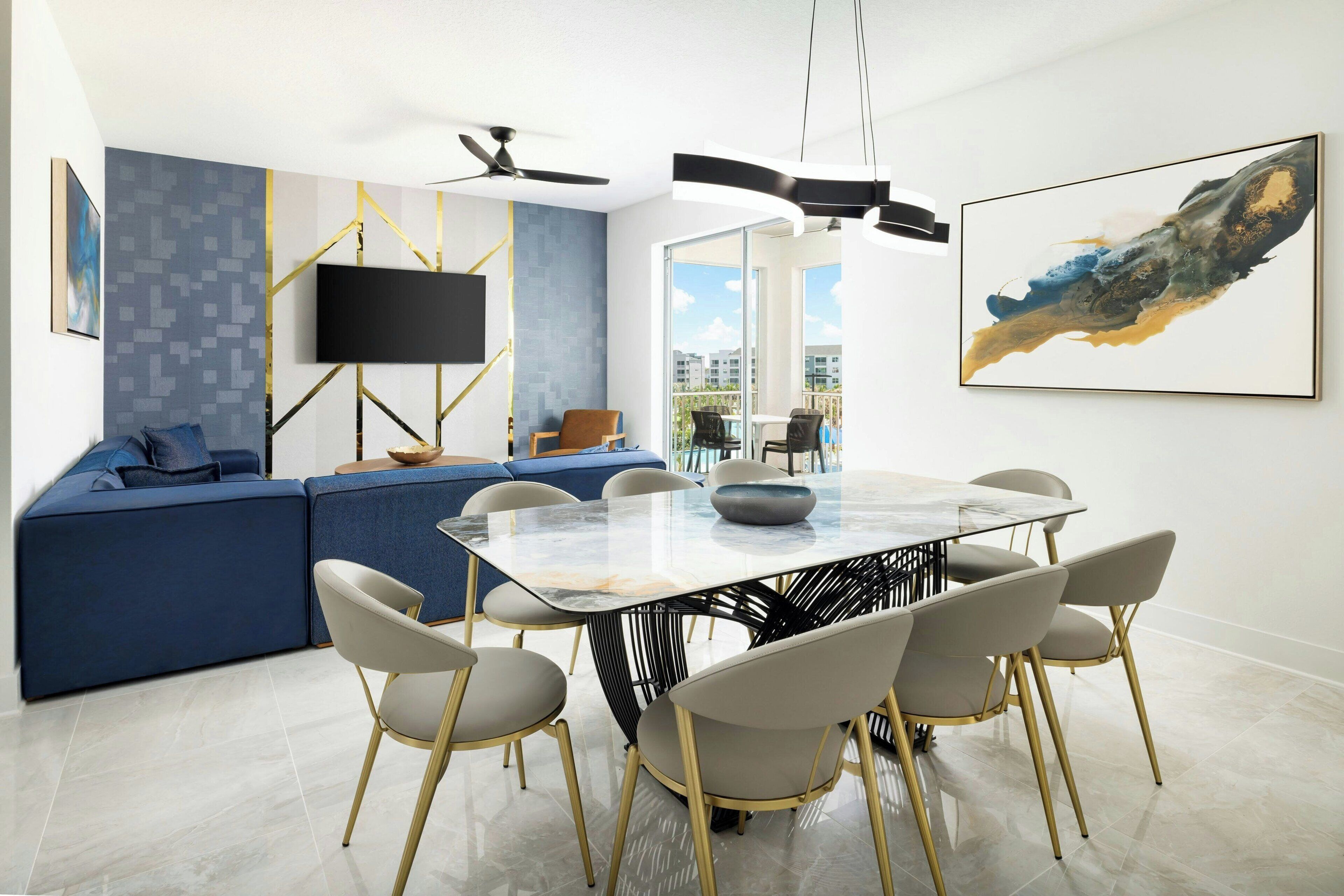 Una sala de estar moderna con un sofá modular, una mesa de comedor con sillas, un televisor de pantalla plana y un ventilador de techo.
