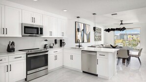 Una cocina moderna con armarios blancos, electrodomésticos de acero inoxidable y un comedor con vistas.