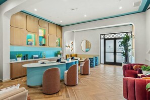 A modern hotel lobby with a reception desk, seating area, and a large mirror. - Villatel Resort Orlando, Apartments by Marriott Bonvoy (Orlando)