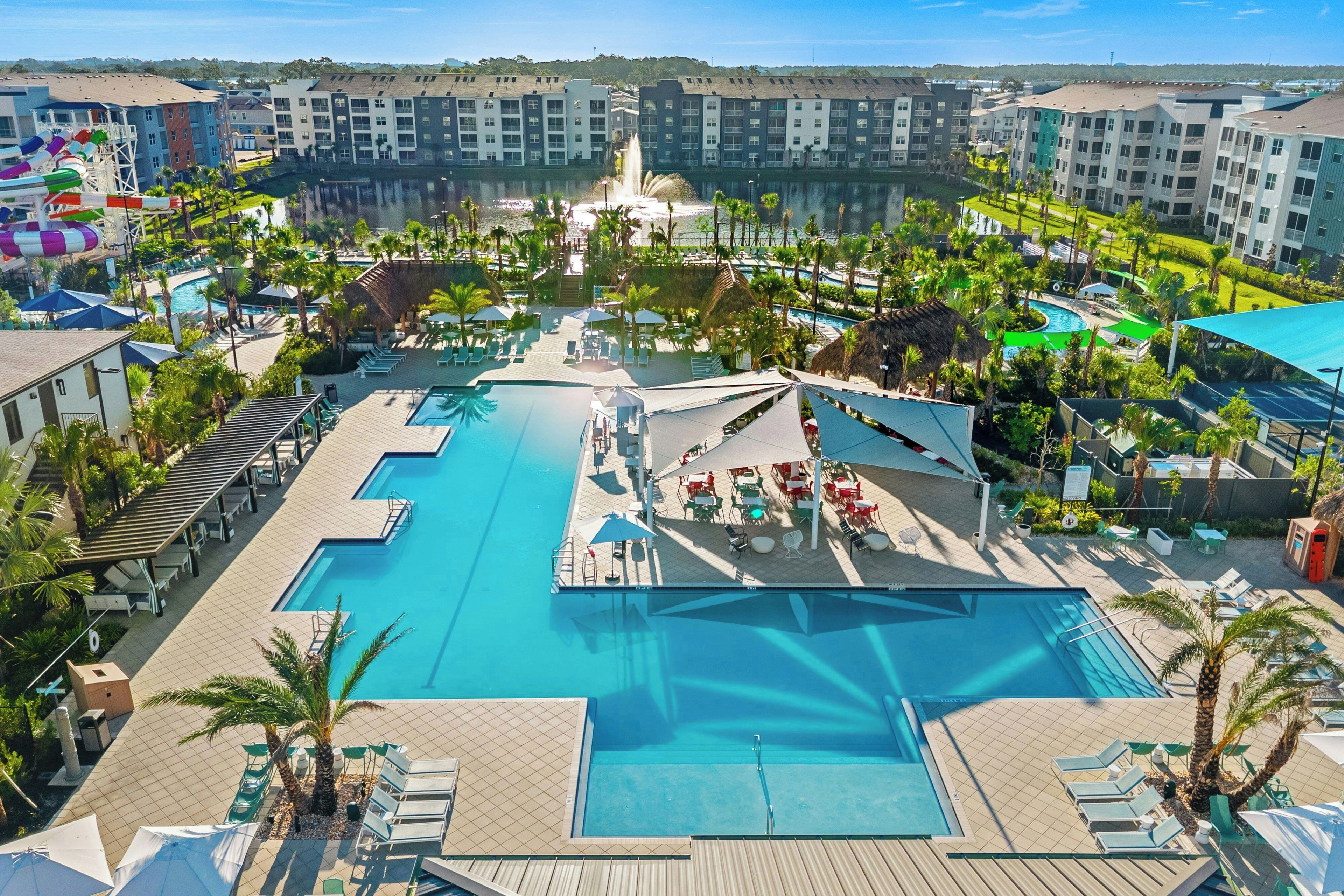 Un resort con una piscina central, varias zonas de descanso y vistas de los edificios circundantes.