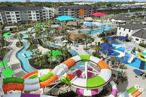 A resort with multiple swimming pools, a water slide, and a variety of umbrellas. - Villatel Resort Orlando, Apartments by Marriott Bonvoy (Orlando)