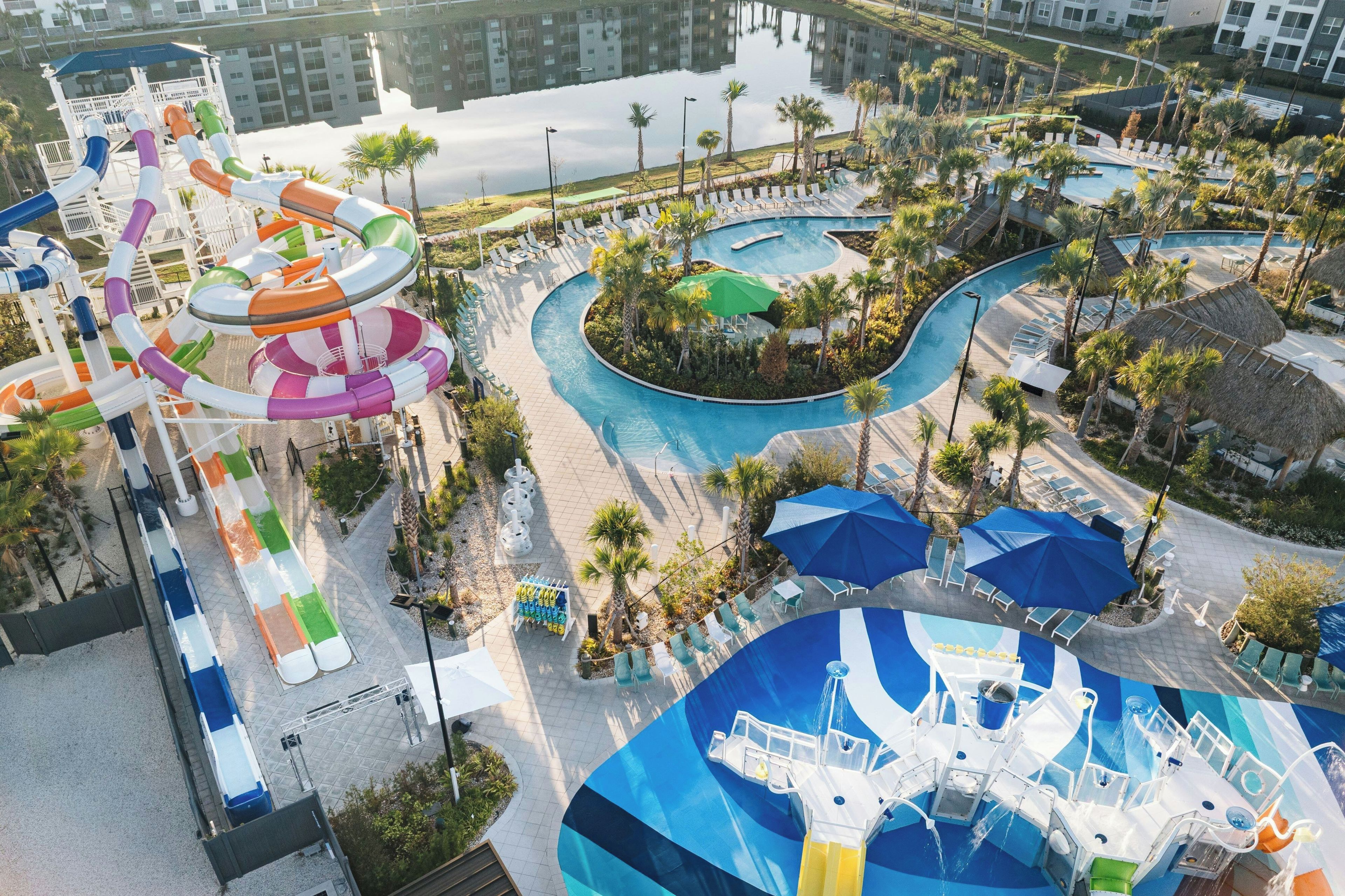 A water park with multiple slides and pools, surrounded by lounge areas and palm trees.