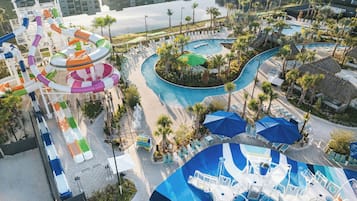 A water park with multiple slides and pools, surrounded by lounge areas and palm trees.