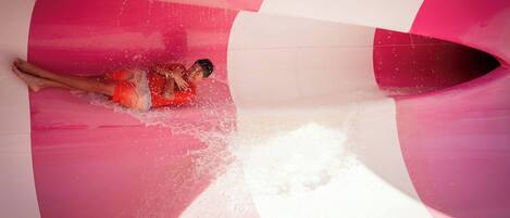 A person sliding down a curved, multi-colored slide with water splashing around.