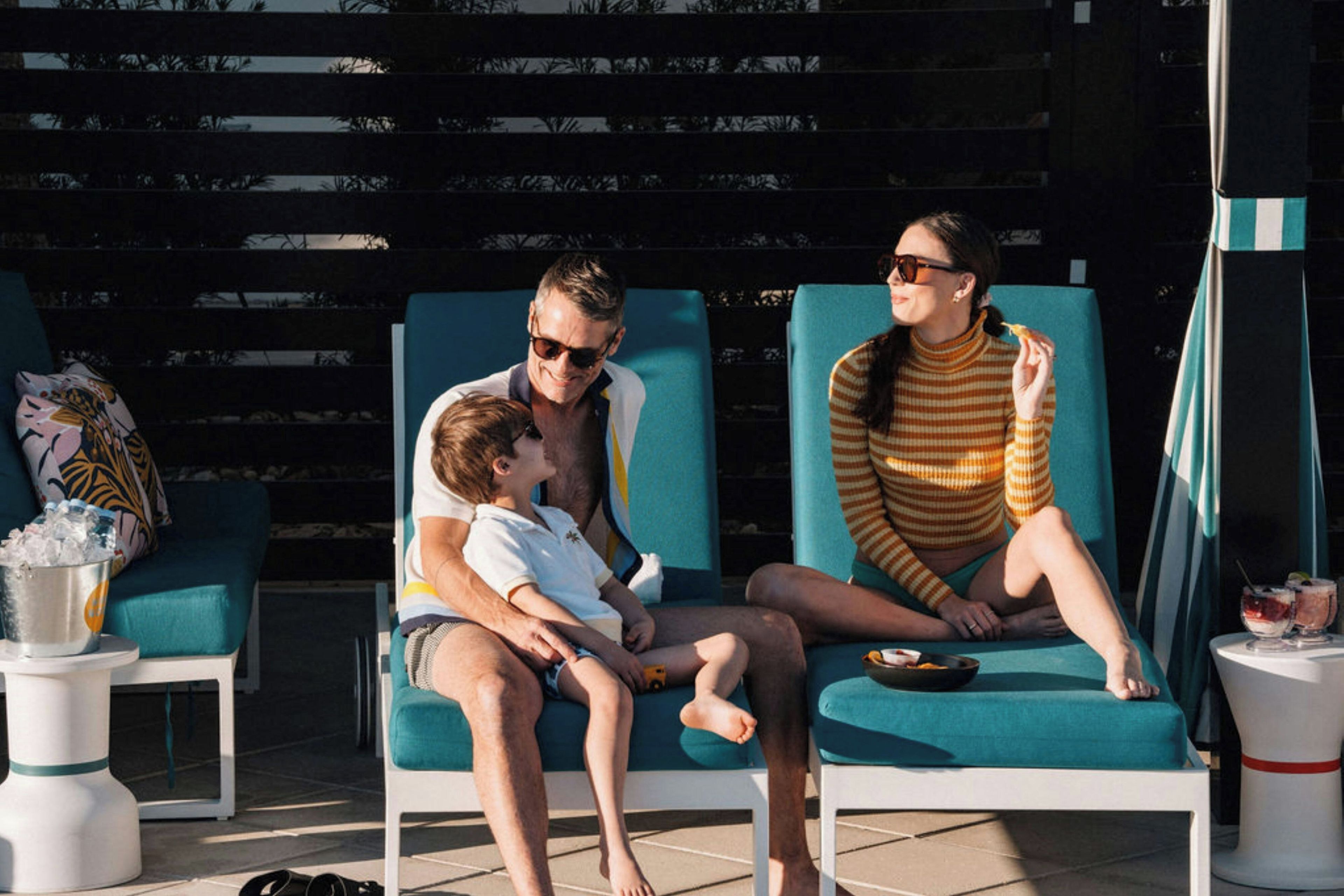 A poolside area with lounge chairs, a child, and an adult.