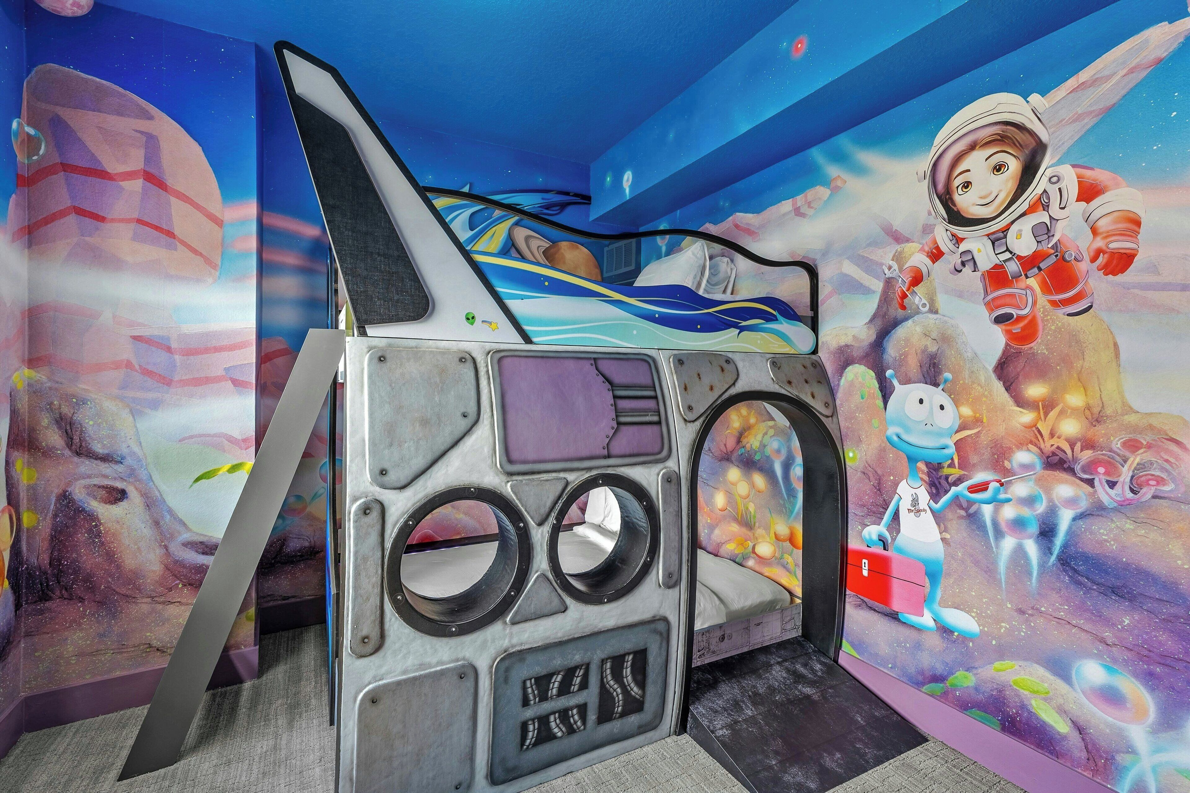 Habitación infantil con un mural de temática espacial, una cama litera y un ventanal grande.