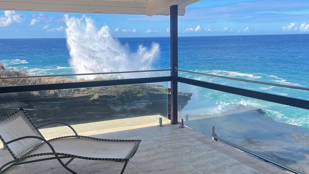 A balcony with a view of the ocean, a chair, and a tiled floor. - Glam Mid Century Modern 4-bedroom oceanfront estate in wonderful Honolulu (Honolulu)