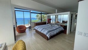 A modern bedroom with a large bed, a seating area, and a view of the ocean. - Glam Mid Century Modern 4-bedroom oceanfront estate in wonderful Honolulu (Honolulu)