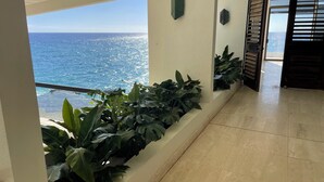A hallway with a view of the ocean, potted plants, and a door leading to another room. - Glam Mid Century Modern 4-bedroom oceanfront estate in wonderful Honolulu (Honolulu)
