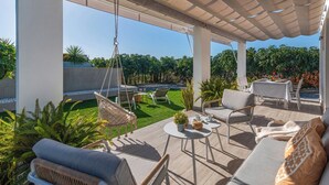 A covered outdoor patio with seating, a hanging chair, and a table with a potted plant. - Villa El Rincón de Lupe Torrox by Ruralidays (Málaga)