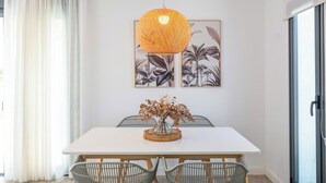 A dining area with a white table, wicker chairs, a woven hanging light fixture, and two framed botanical prints on the wall. - Villa El Rincón de Lupe Torrox by Ruralidays (Málaga)