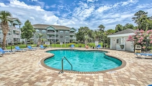 A swimming pool with a 3ft depth marker, surrounded by lounge chairs and a brick patio. - First Floor Updated Coastal Summer Retreat at Magnolia Place - Pool View (Myrtle Beach)