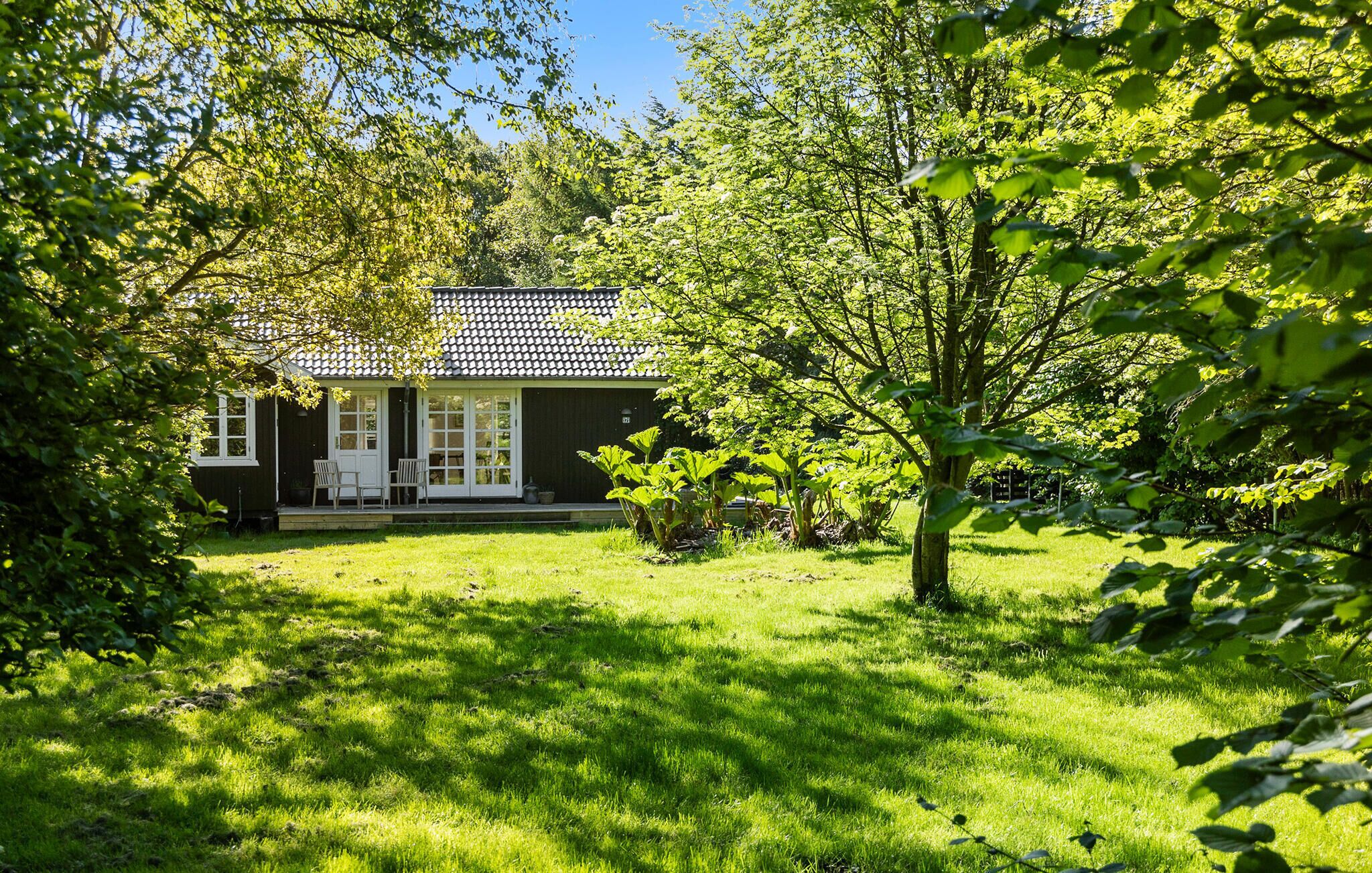A house with a tiled roof, a front porch, and a well-maintained lawn.