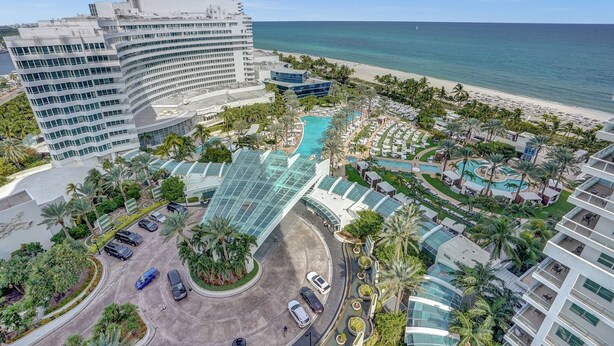 Un complexe hôtelier doté de plusieurs piscines, d’un grand bâtiment principal et d’une plage.