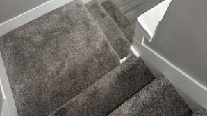 Een trap met een bordje dat wijst op een lage overkapping, bekleed met tapijt en voorzien van een leuning.