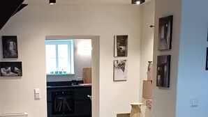 Moderni sisustus, jossa keittiö näkyy taustalla, ruokailutila pöytineen ja tuoleineen sekä punainen tuoli etualalla.