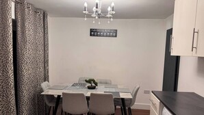 A modern dining area with a table set for four, a chandelier, and a coffee menu sign on the wall.