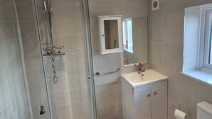A modern bathroom with a glass-enclosed shower, a vanity with a mirror, and a toilet.