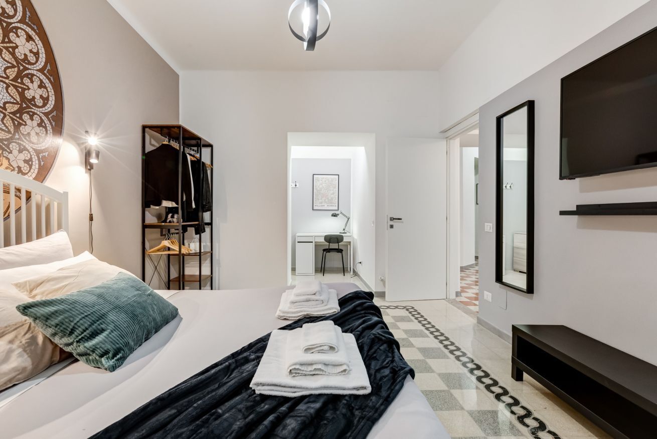 A hotel room with a bed, a wardrobe, a desk, and a TV.