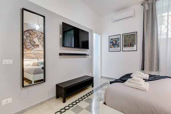 A modern bedroom with a bed, a TV, a bench, and artwork on the walls.
