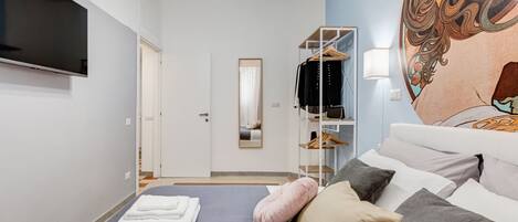 Een hotelkamer met een bed, een televisie, een kledingkast en een muurschildering.