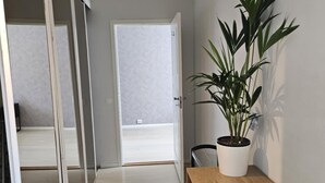 A hallway with a wooden bench, a potted plant, and a sliding door leading to a balcony. - Free Parking Space, Balcony, Prime Location (Ålesund)