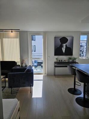 A modern living room with a sofa, a dining table, and a large window. - Free Parking Space, Balcony, Prime Location (Ålesund)