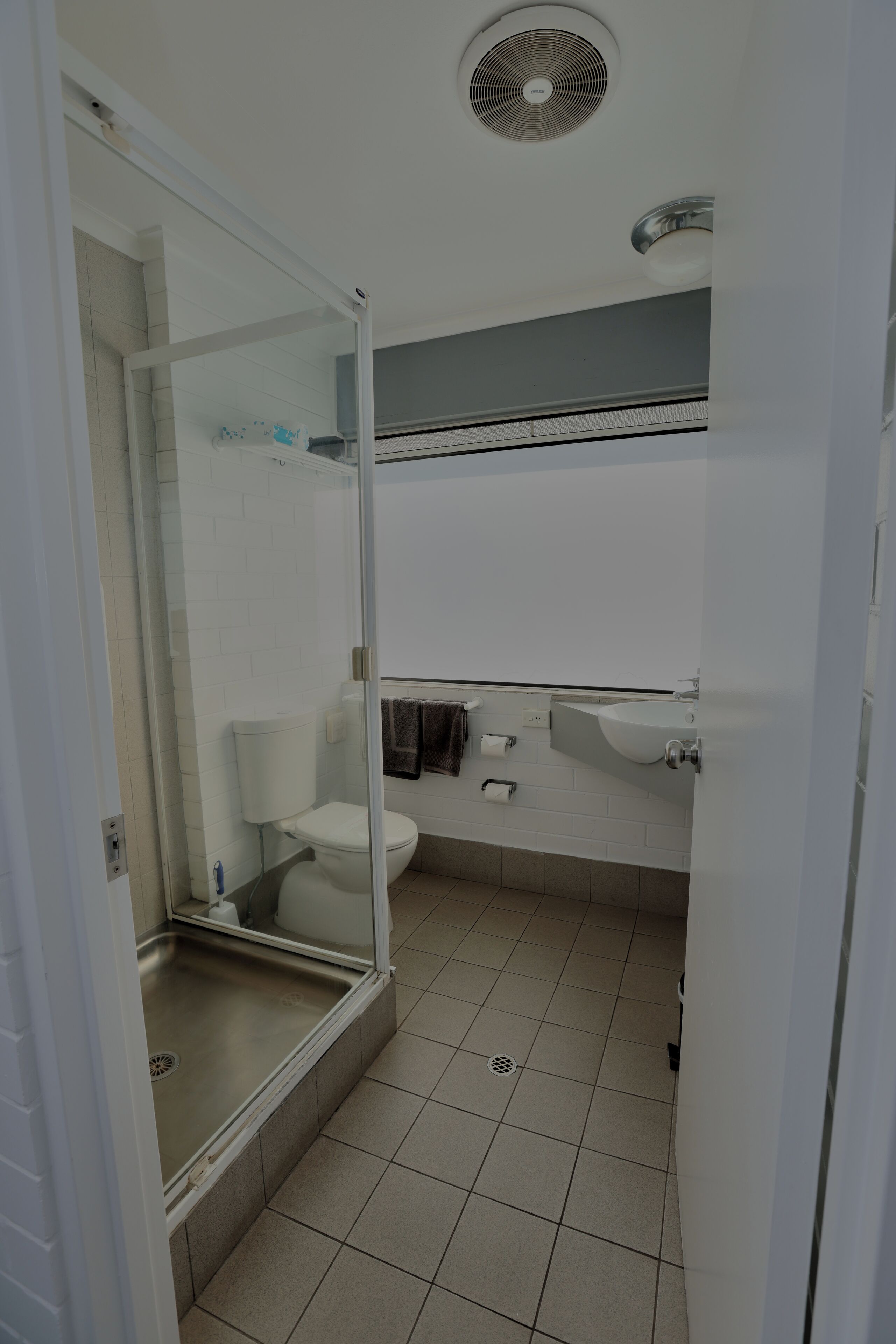 Un baño con cabina de ducha de vidrio, inodoro, lavamanos y espejo.