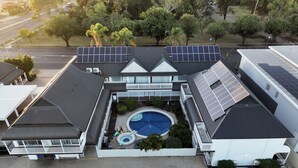 An aerial view of a building with a swimming pool, solar panels, and a parking lot. - Dalby Manor Motor Inn  (Dalby)