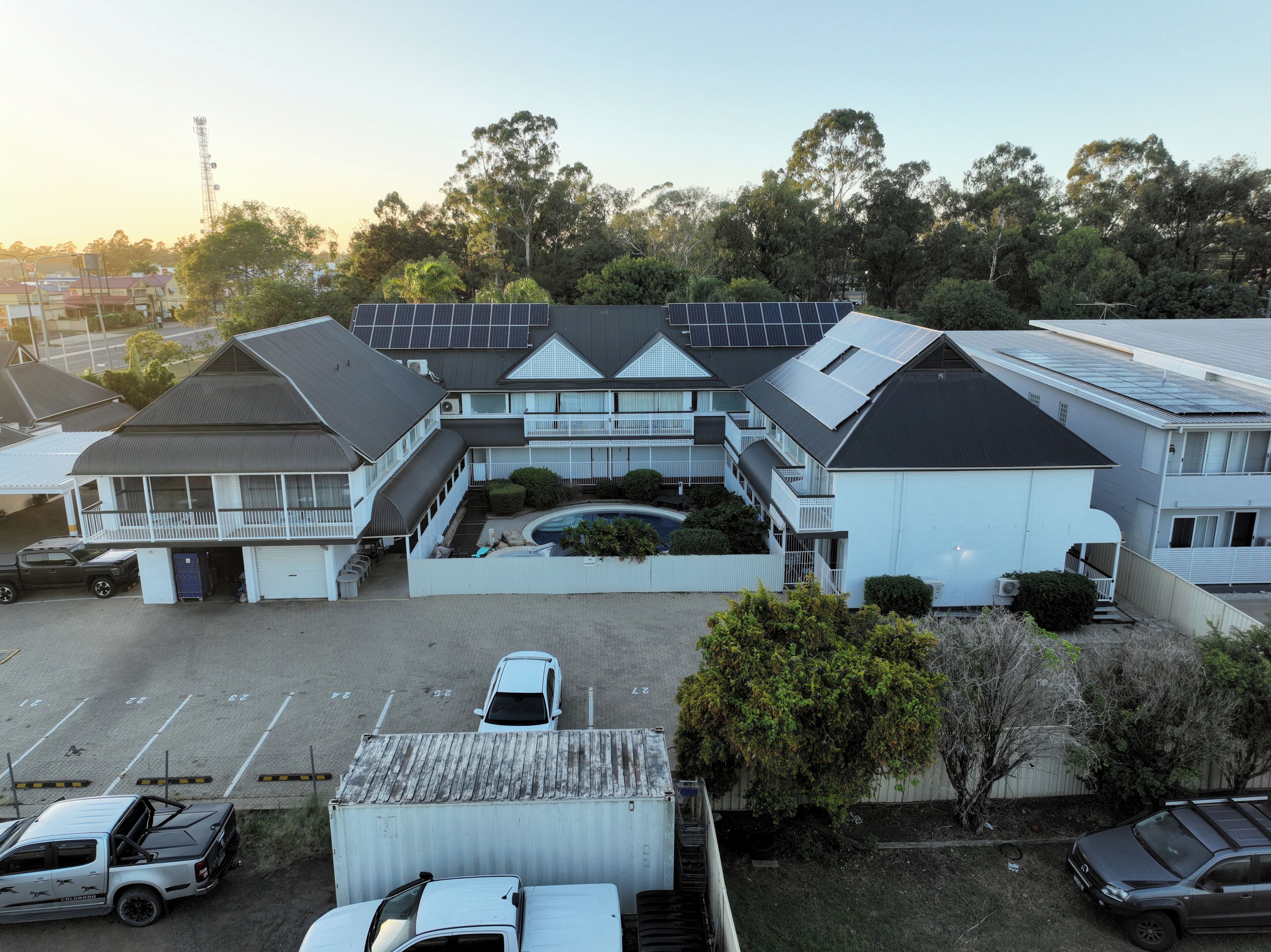 A residential building with multiple units, a swimming pool, and solar panels on the roof.