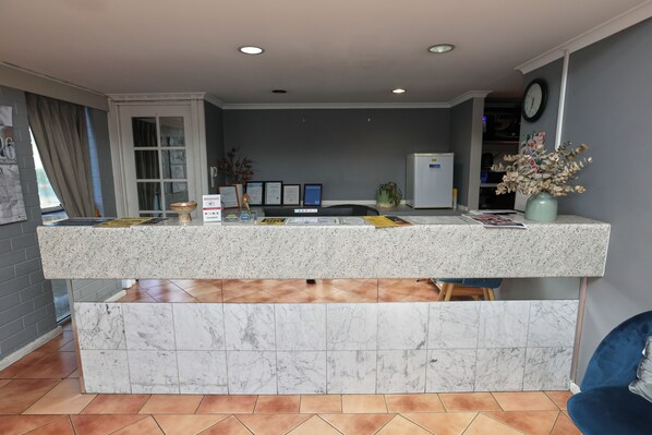 A reception area with a marble counter, a clock, and a vase of flowers.
