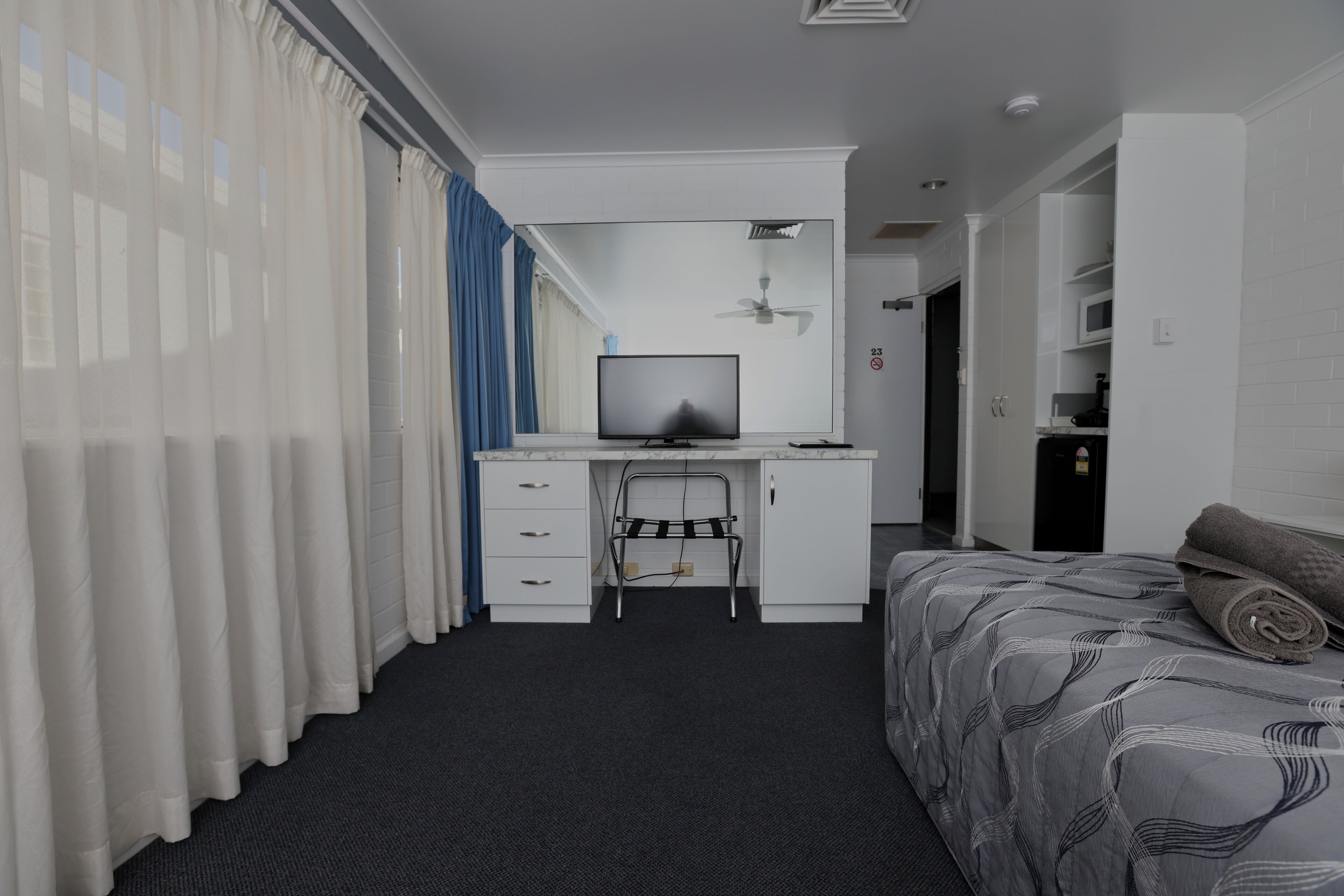 Une chambre d’hôtel équipée d’un lit, d’un bureau avec un ordinateur, d’une télévision et d’un four à micro-ondes.