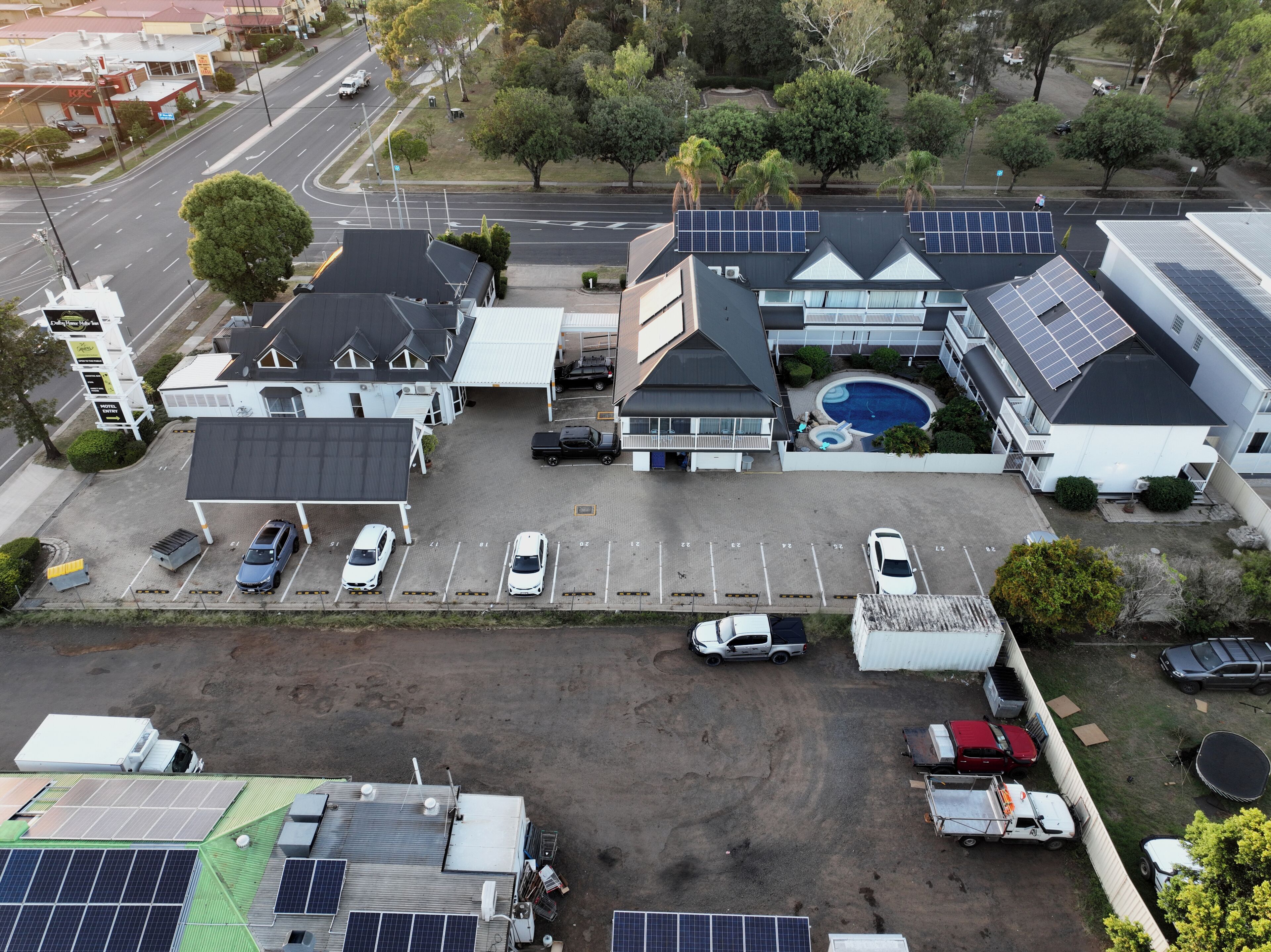 Vue aérienne d’un hôtel doté de nombreux espaces de stationnement, d’une piscine et de panneaux solaires sur le toit.