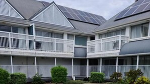 A swimming pool with a hot tub, surrounded by a brick deck, and a building with balconies in the background. - Dalby Manor Motor Inn  (Dalby)