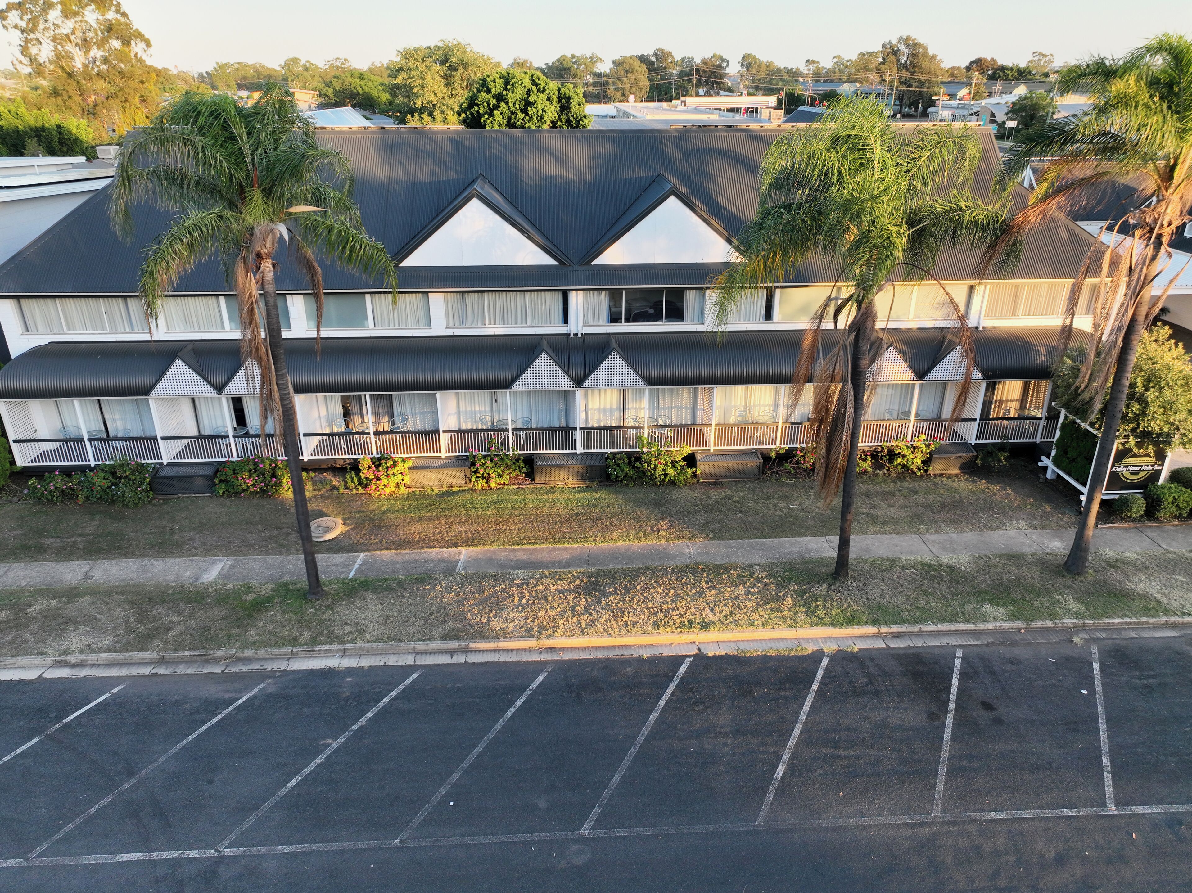 A motel with a row of rooms featuring a balcony and a covered outdoor seating area.