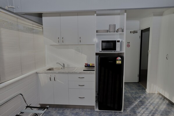 A compact kitchen with white cabinets, a microwave, and a refrigerator.