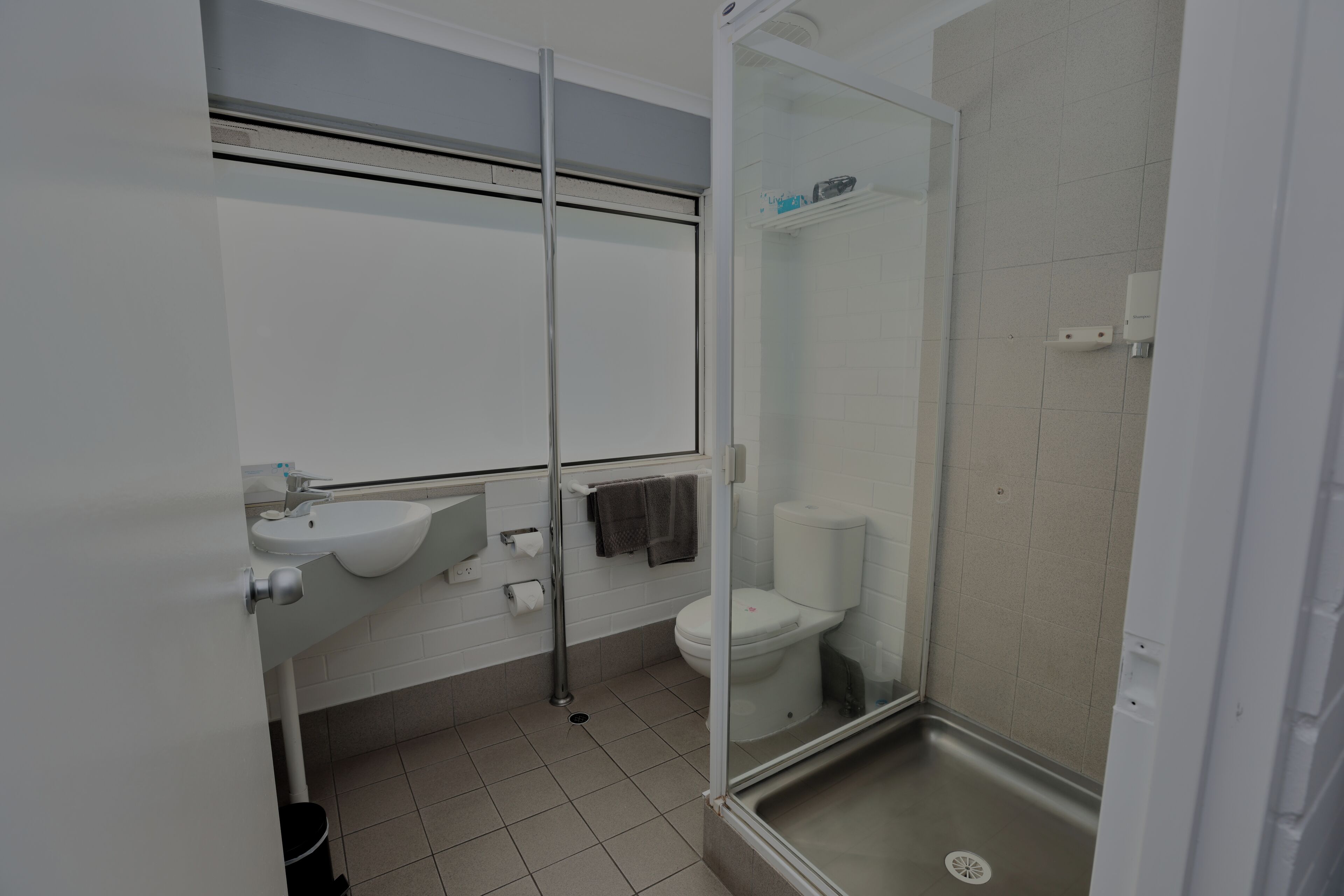 Un baño moderno con cabina de ducha de vidrio, lavamanos blanco y un inodoro.