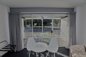 A balcony with a table and chairs, a sofa, and a view of a park and street.