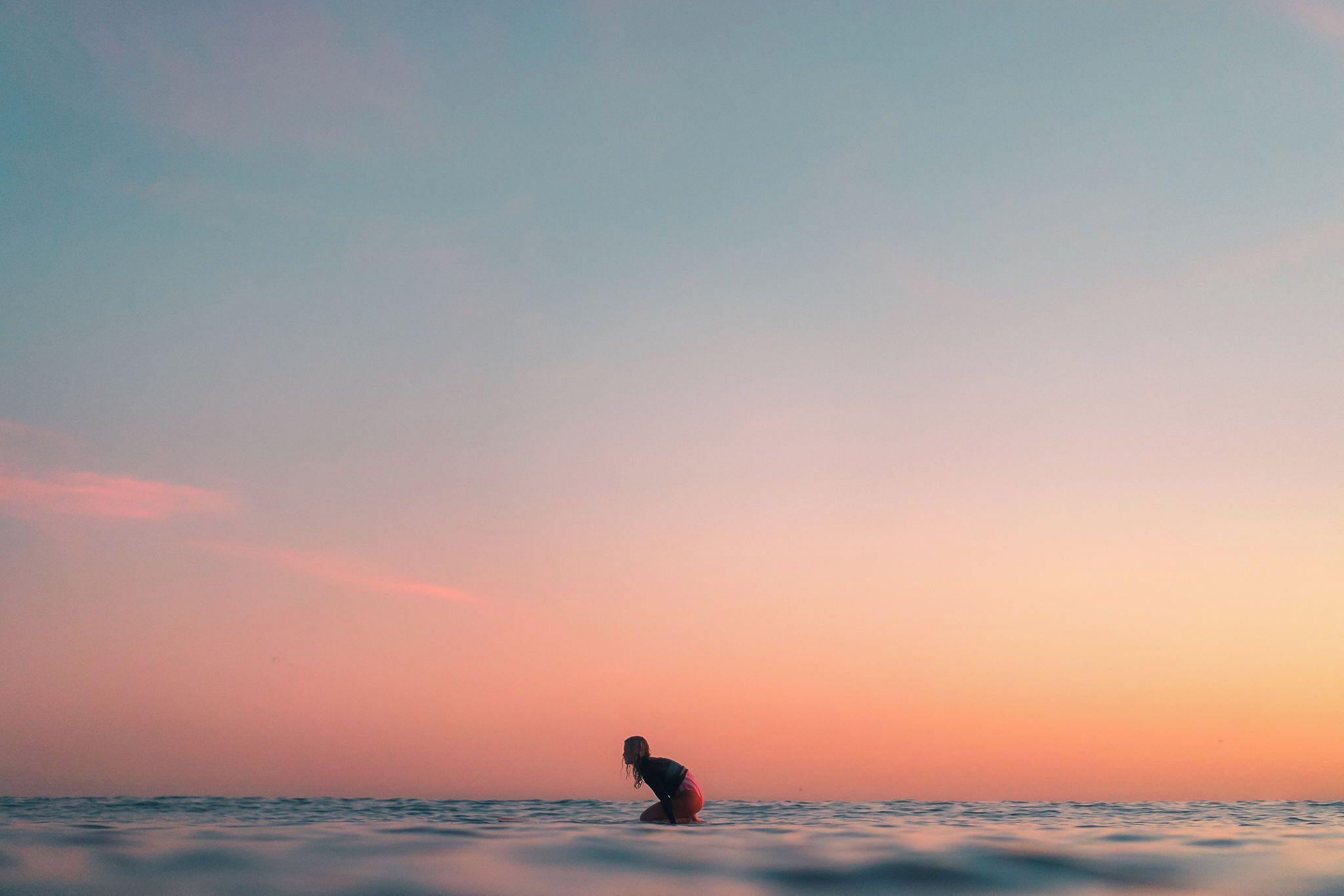 A person standing in the water during sunset.