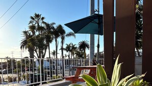 A balcony with potted plants, a metal fence, and a clear blue sky. - West Coast Surf and Stay (San Clemente)