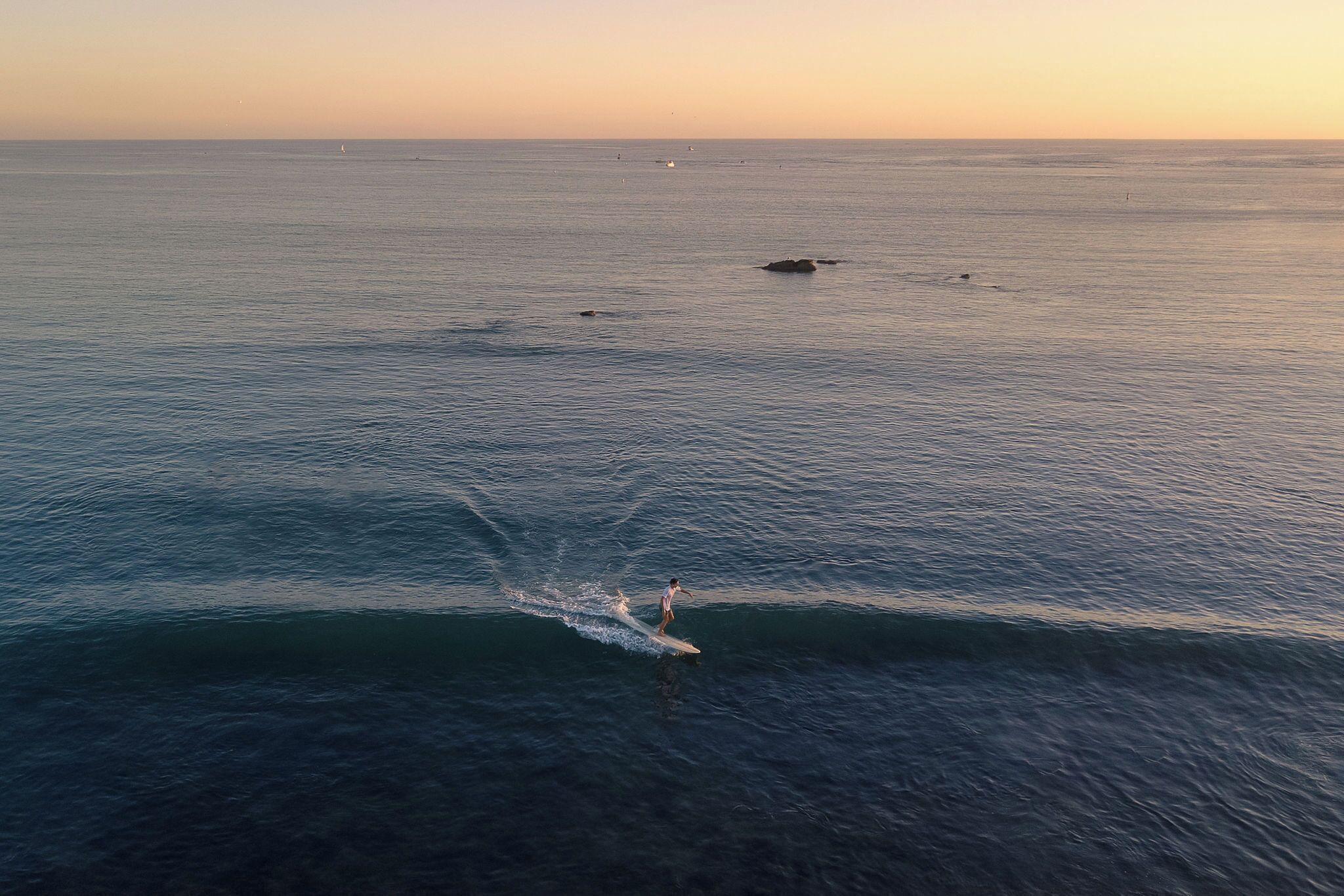 A wide view of a calm sea with a person surfing.