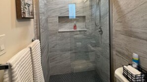 Een kleine badkamer met een douche, toilet en een handdoekhouder.