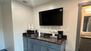 Een moderne keuken met een flatscreen-tv, een magnetron en een koffiezetapparaat op het aanrecht.