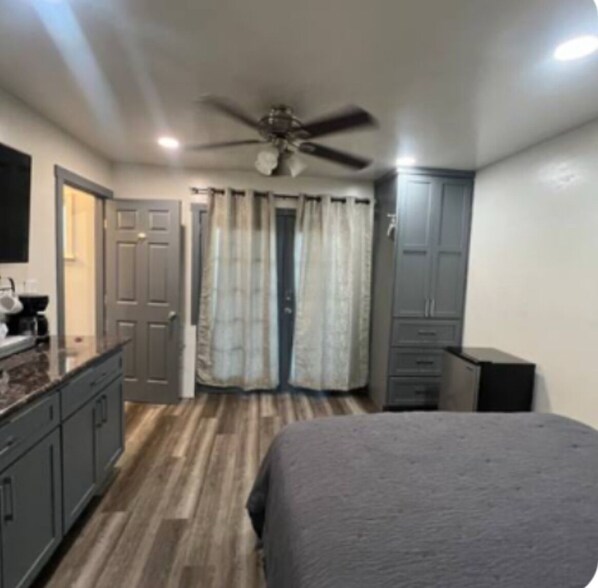 Une chambre à coucher comprenant un lit, un ventilateur de plafond, une armoire et un bureau avec une chaise.
